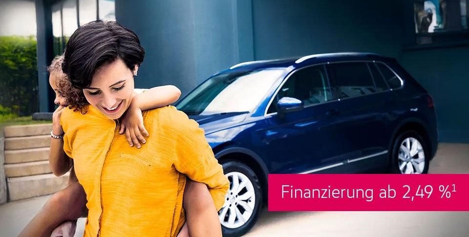 Frau im gelbe Oberteil mit Kind auf dem R&uuml;cken geht sich freuend vom Volkswagen weg, welcher unter einem &Uuml;berdach steht. Ein St&ouml;rer mit "Finanzierung ab 2,49 %"